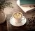 café espresso com desenho de flor em xícara e pires cor branca em cerâmica na mesa junto com flor e livro