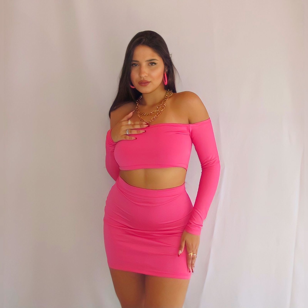 Uma roupa rosa e verde com um top rosa e saia rosa.