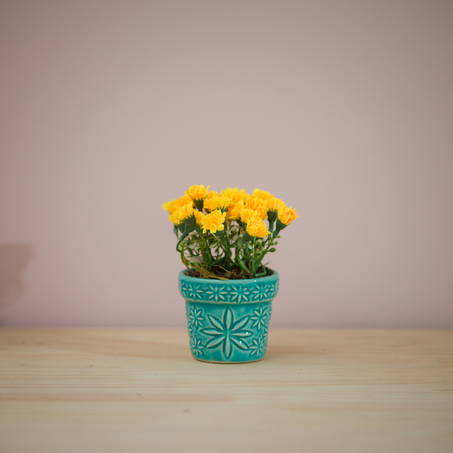 Vaso azul turquesa com arranjo de flores artificiais amarela