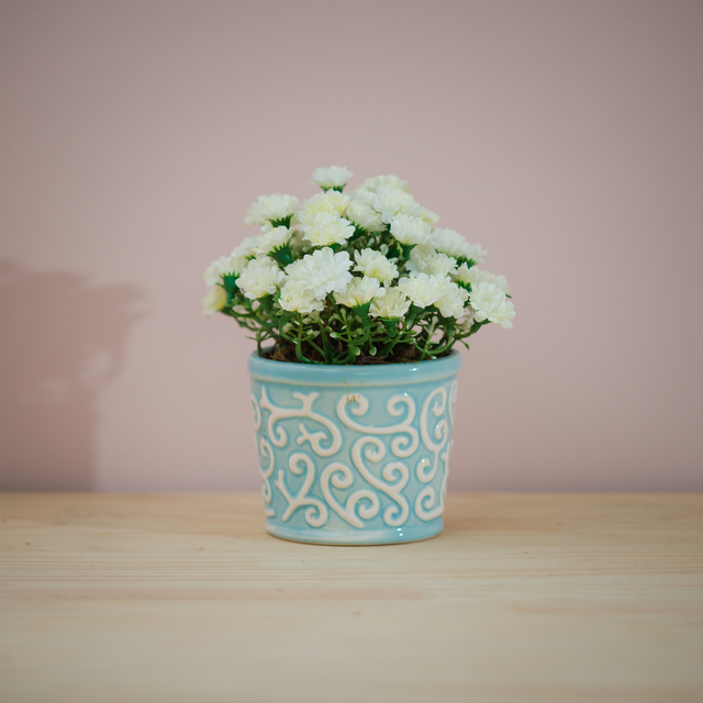 Vaso azul claro com arranjo de flores artificiais brancas