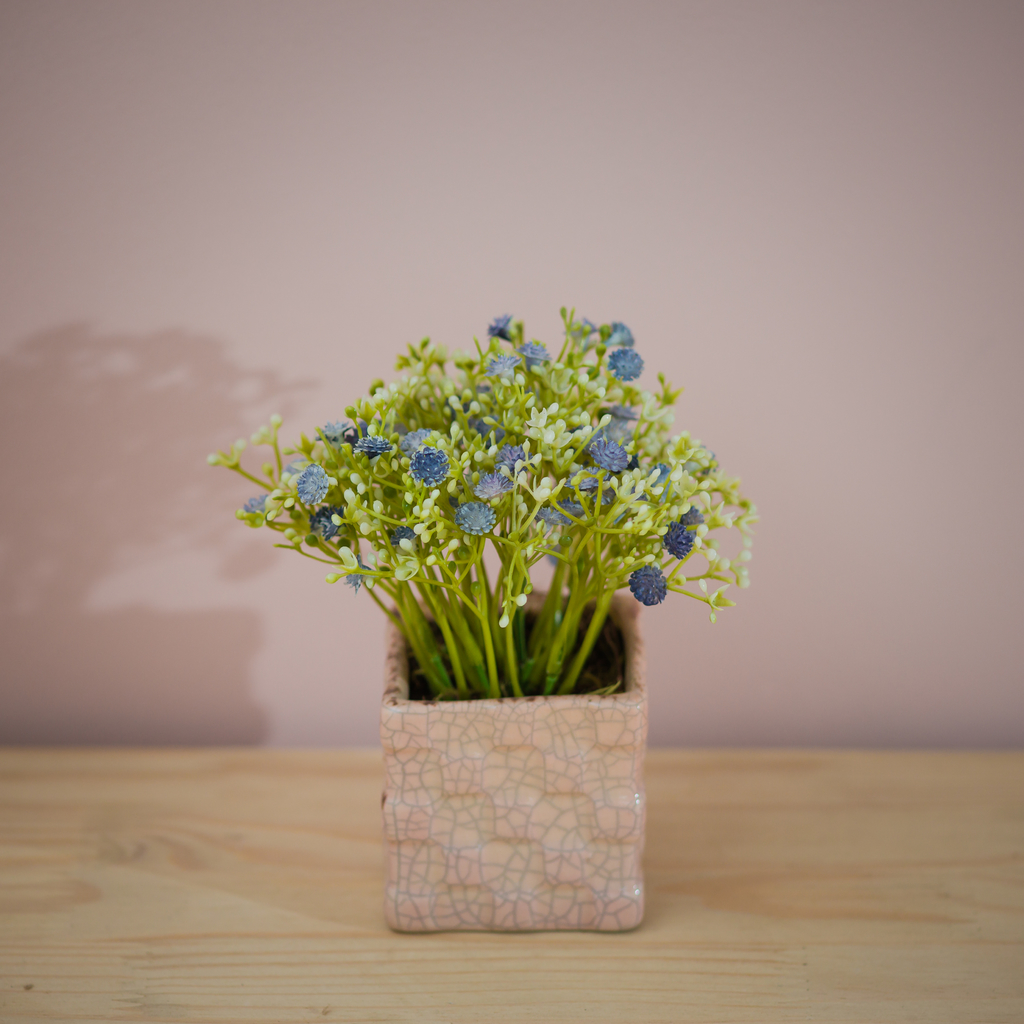 Vaso rosa claro com arranjo de flores artificiais azuis