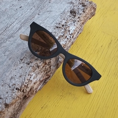 anteojos de sol de madera (patillas) y acetato negro (frente) con lentes polarizados marca Nomade. vista con anteojo reclinado