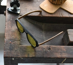 anteojos de madera (patillas), acetato (frente) color negro y aplique de acero inoxidable con lentes tintados color amarillo vista cenital | Nomade